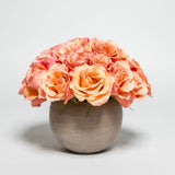 A beautifully arranged rose pave flower arrangement with mocaccino Ecuadorian roses in a brown-toned clay vase on a white background.